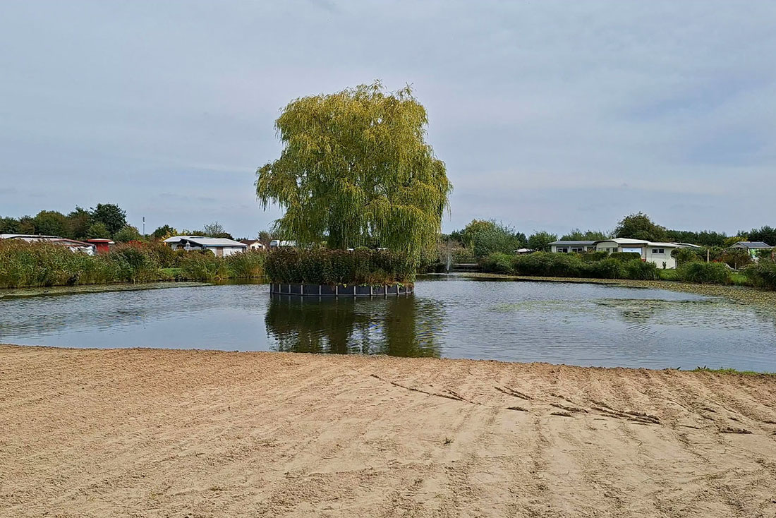 Sandy beach by the swimming pond at naturist campsite De Brongaard